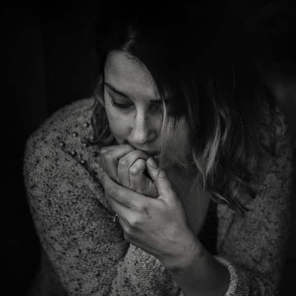 A young woman sitting alone, overcome by emotion, with tears streaming down her face - illustrating the emotional distress and how to use DBT for trauma survivors.