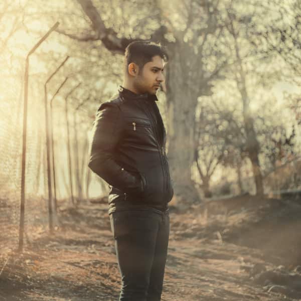 A man standing in a foggy forest, gazing intently into the near distance, symbolizing reflection and introspection in the context of narrative therapy.