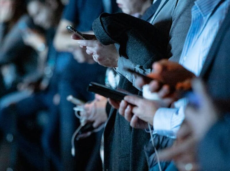 A group of diverse individuals engrossed in their smartphones, possibly experiencing FOMO as they scroll through social media.