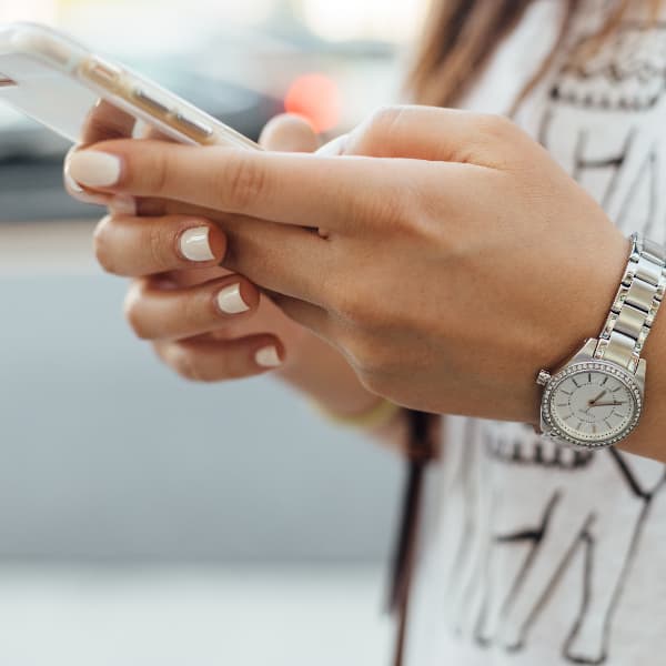 Close-up of a woman's hand holding a phone displaying a vibrant social media feed, symbolizing the potential trigger for FOMO.