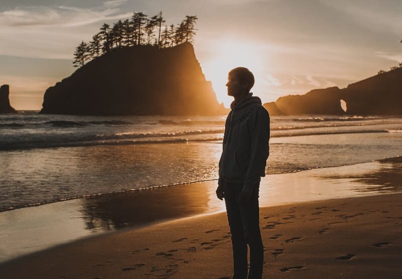 Man taking a reflective walk on an Orange County, CA beach, symbolizing the mental wellness journey through IOP.