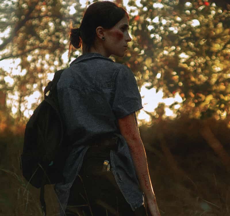 Woman in a forest, pensively looking to the side, the surrounding trees echoing the complexity and signs of disassociation she might be experiencing.