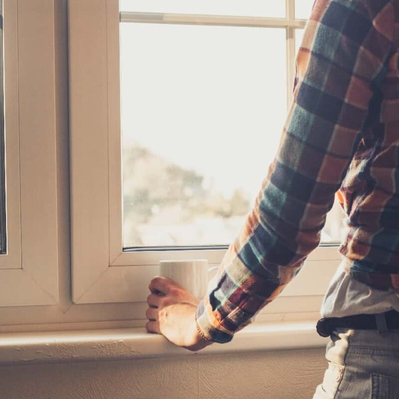 Man gazing out a window, reflecting on untreated mental health issues.