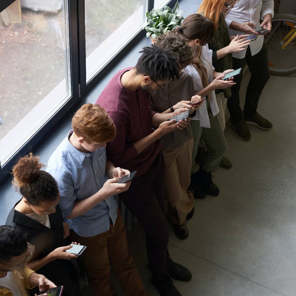 A group of individuals engrossed in their smartphones, symbolizing modern escapism and digital distractions.