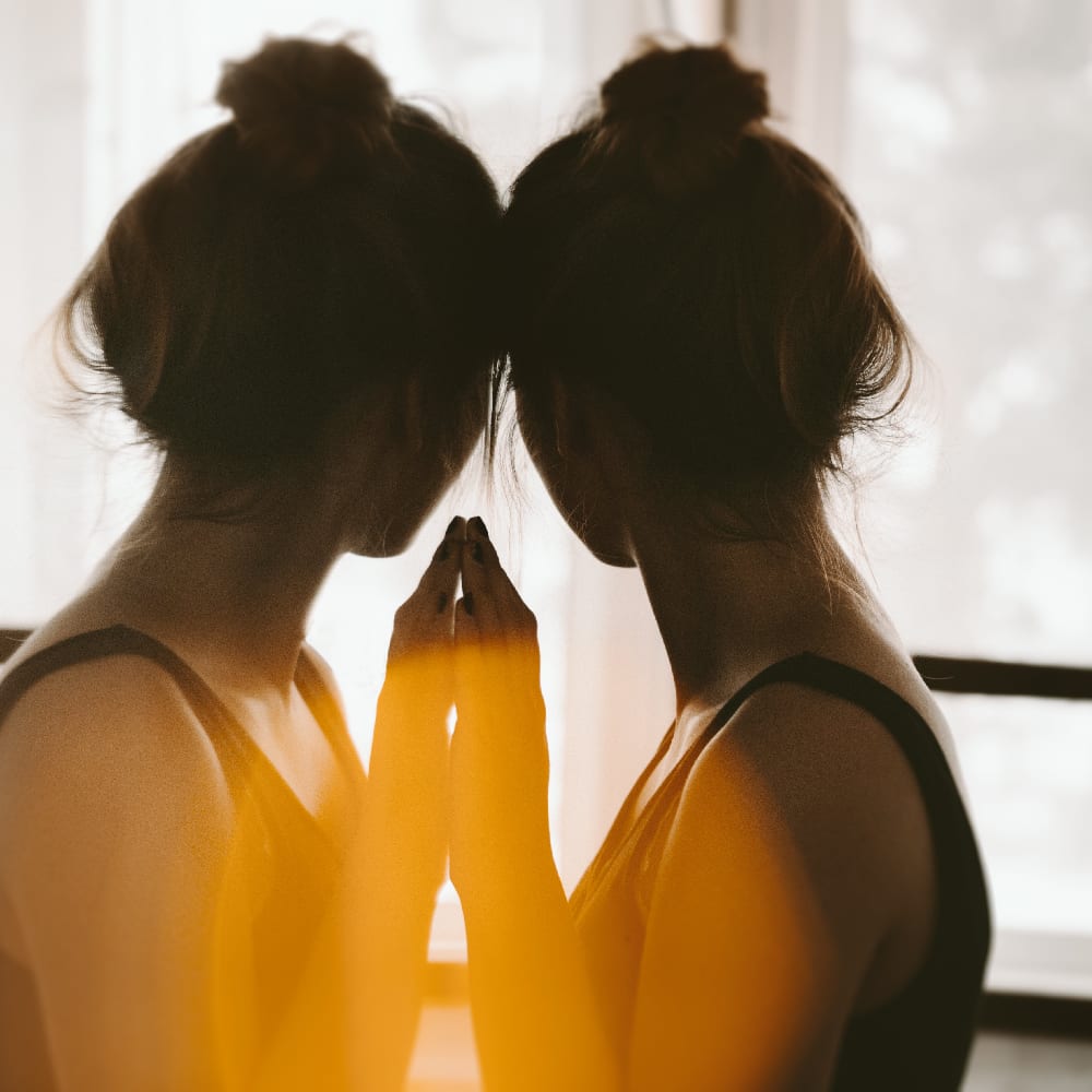 A woman stands in front of a mirror highlighting the theme of distorted self-perception, relevant to the article discussing facts about anorexia.