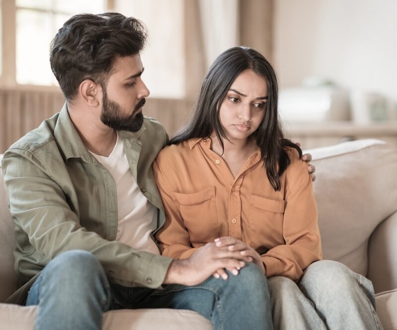 Male bearded man and his wife sitting on the couch talking about mental health treatment