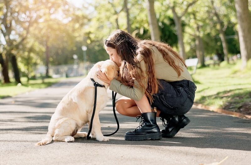 Female dog walker with anxiety and depression kneeling on the street with a dog