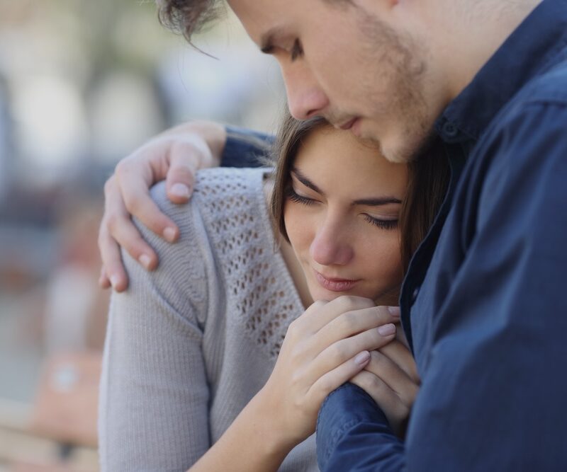 Man hugging and comforting a woman who has lost a loved one