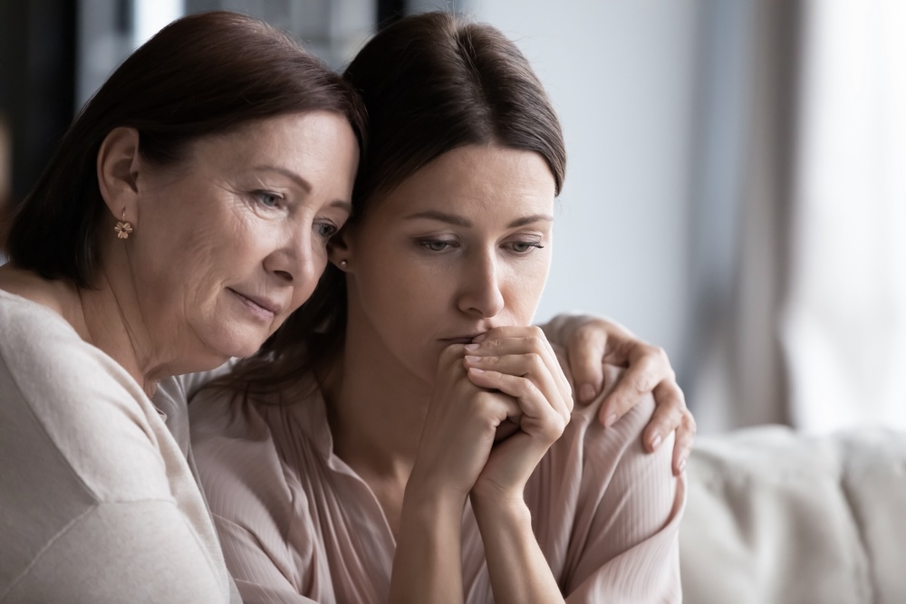 Elderly woman comforting her daughter who is grieving and dealing with depression