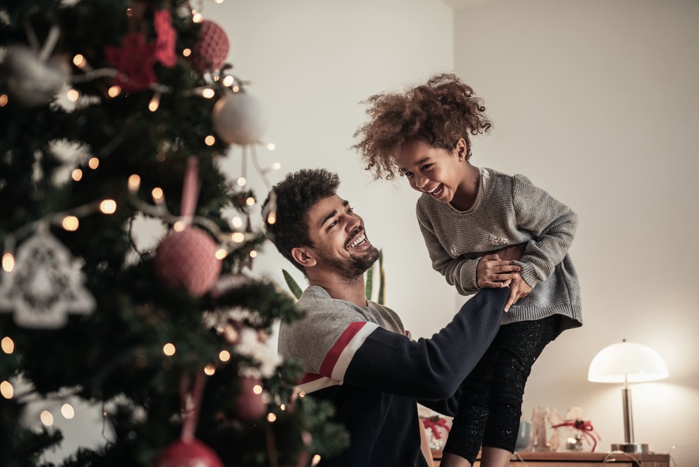 Father playing with his son near the Christmas tree