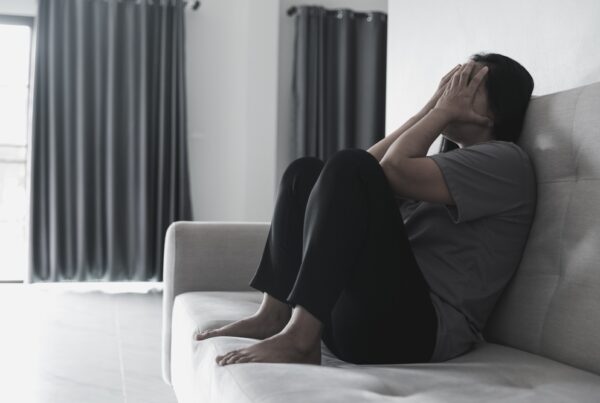 Woman with schizophrenia sitting on the couch struggling with symptoms