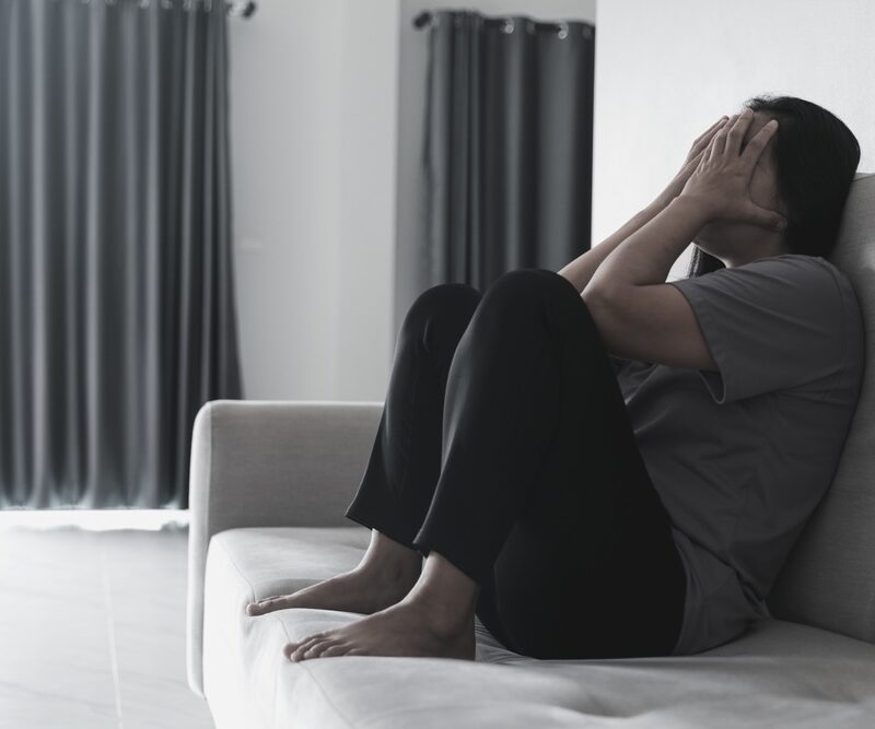 Woman with schizophrenia sitting on the couch struggling with symptoms