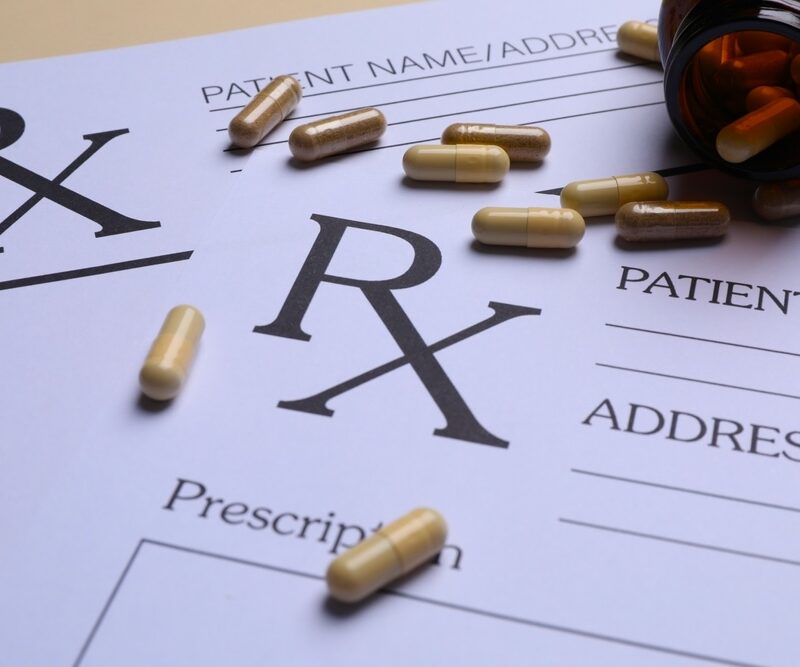 Close-up of a prescription pad with scattered medication from a brown bottle