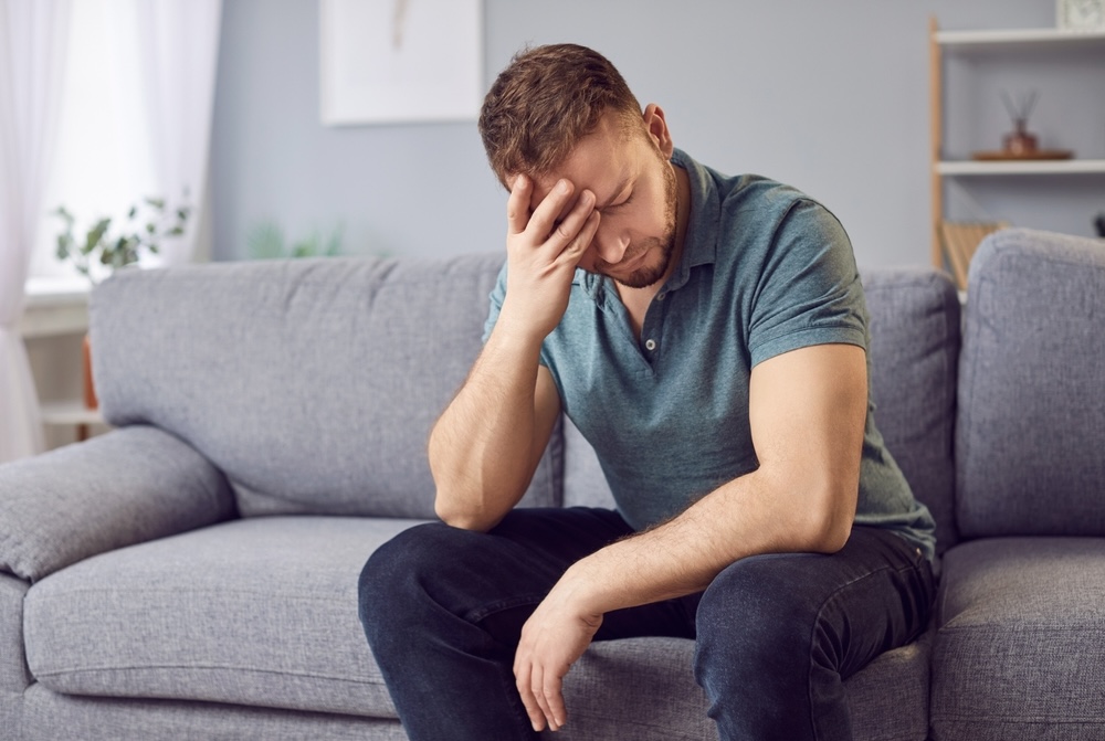 Man sitting on a couch feeling depressed due to a breakup with his partner