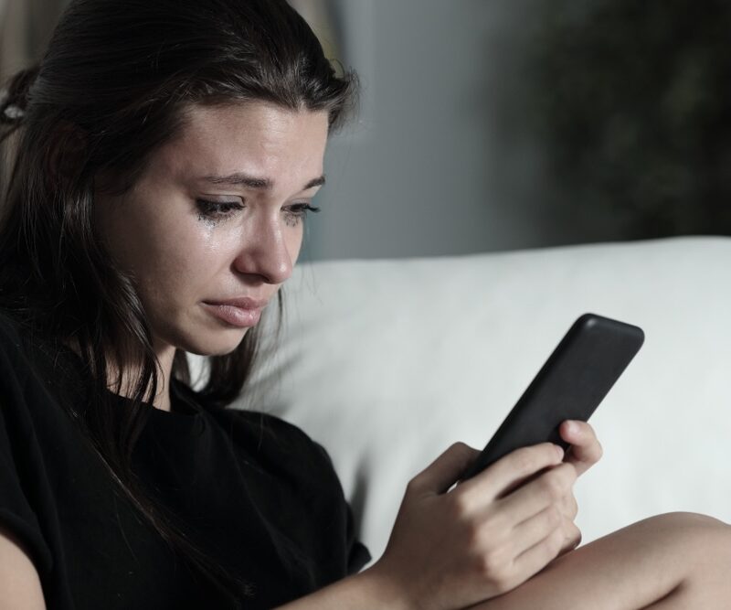 Female crying while texting to get mental health help